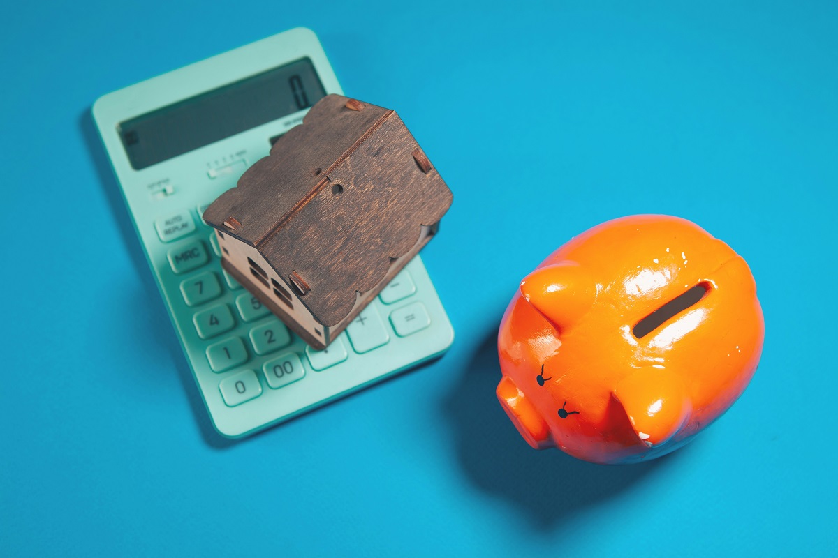 calculator, miniature house, and piggy bank